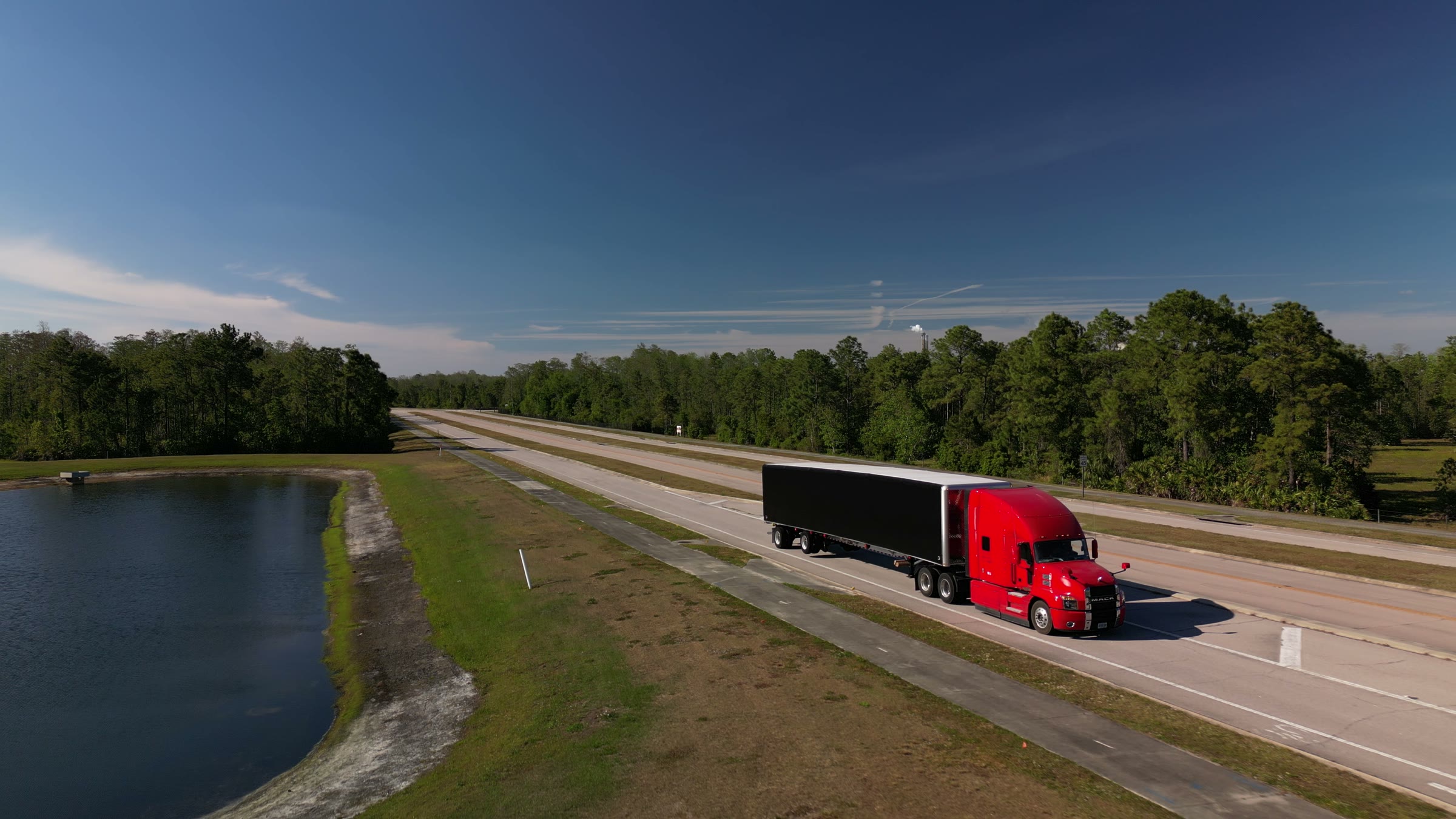 A League Trucking Mack pulling a conestoga down the highway, seen from a drone.